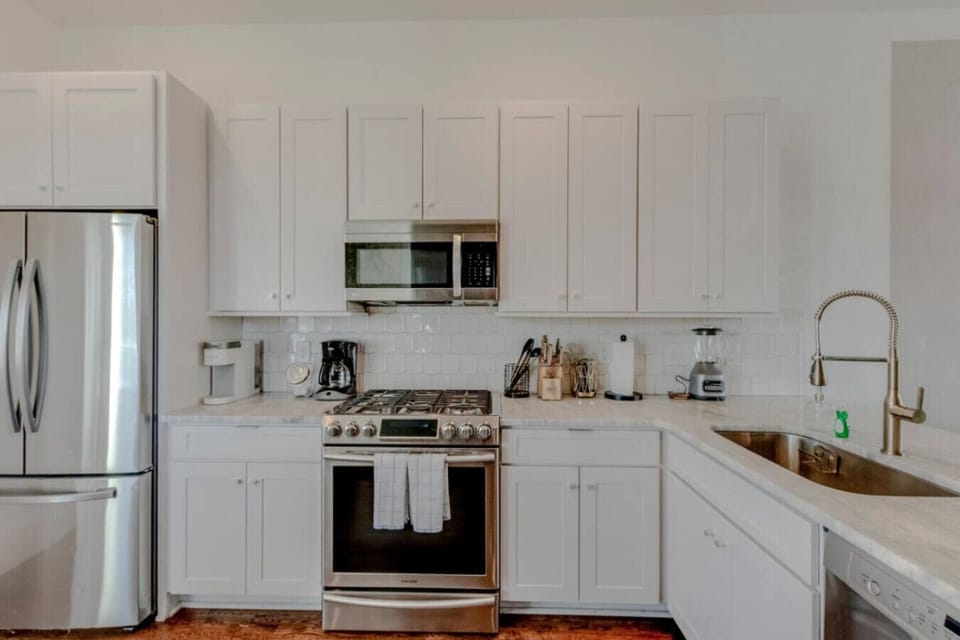 Kitchen from corner showing stainless range, coffee maker, island, and hardwood floors