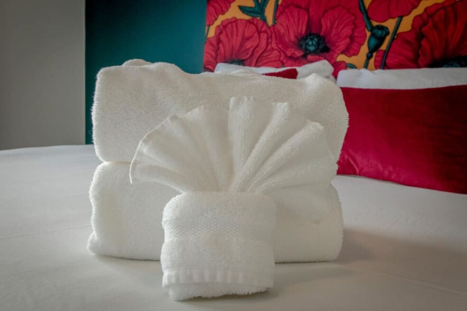 Decorative towel art on bed with red poppy mural background and red pillows