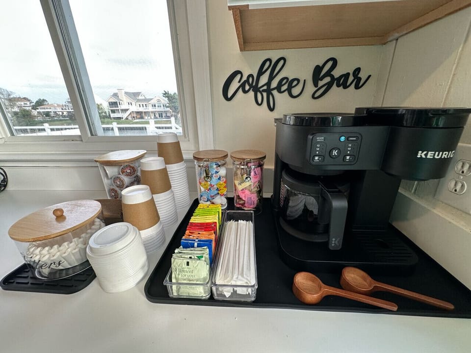Stocked coffee bar with Keurig, K-cups, creamers, sweeteners, and to-go cups, perfect for a quick morning pick-me-up with a view.