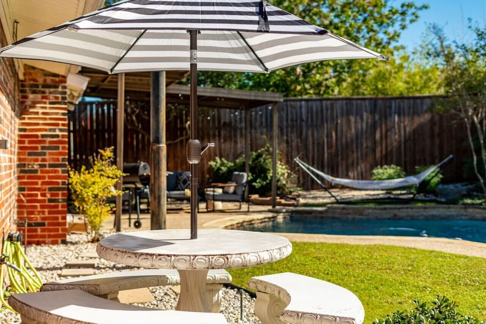 Backyard overlooking the outdoor dining nook, patio, hammock, and pool