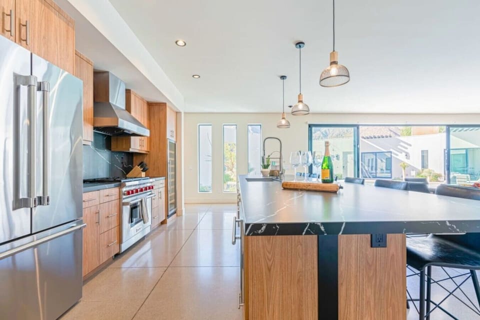 Kitchen w/ stainless fridge, gas range, vent hood & island bar seating.