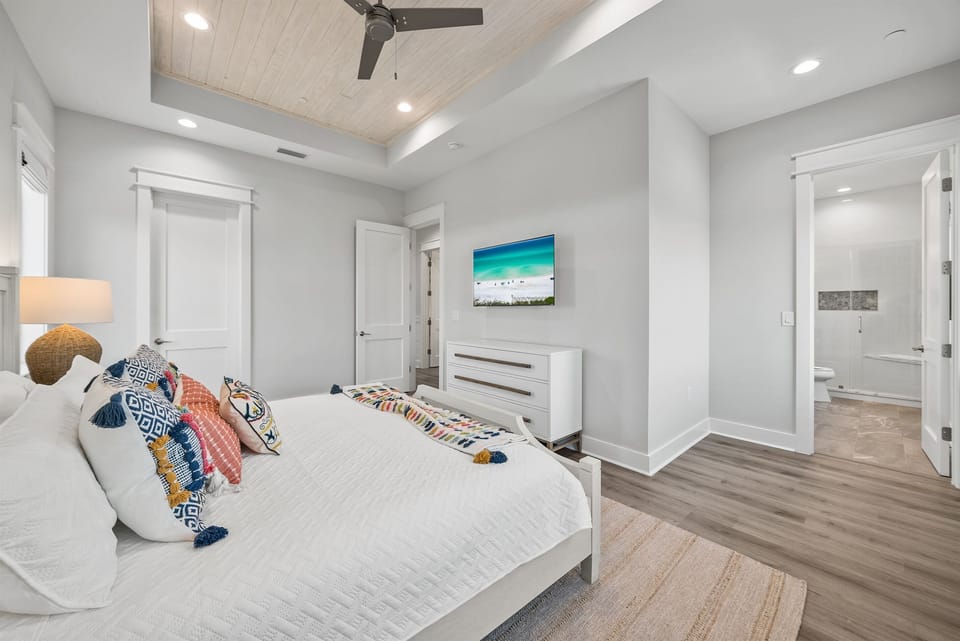 Sink into coastal comfort with vibrant pillows and beach artwork adorning your stylish retreat, complete with ceiling fan and ensuite bath.