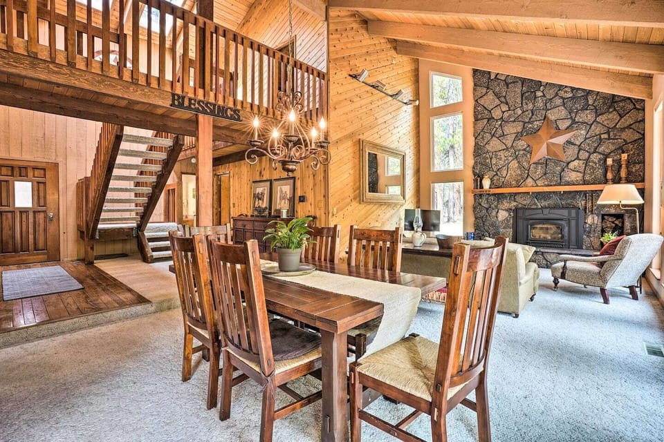 Warm dining room with wood table, high ceilings and staircase backdrop—share meals and stories with family.