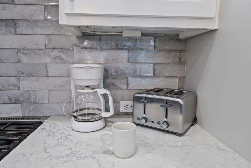 Start your morning right with sleek appliances and marble countertops - your perfect coffee and toast await in this elegant kitchen.