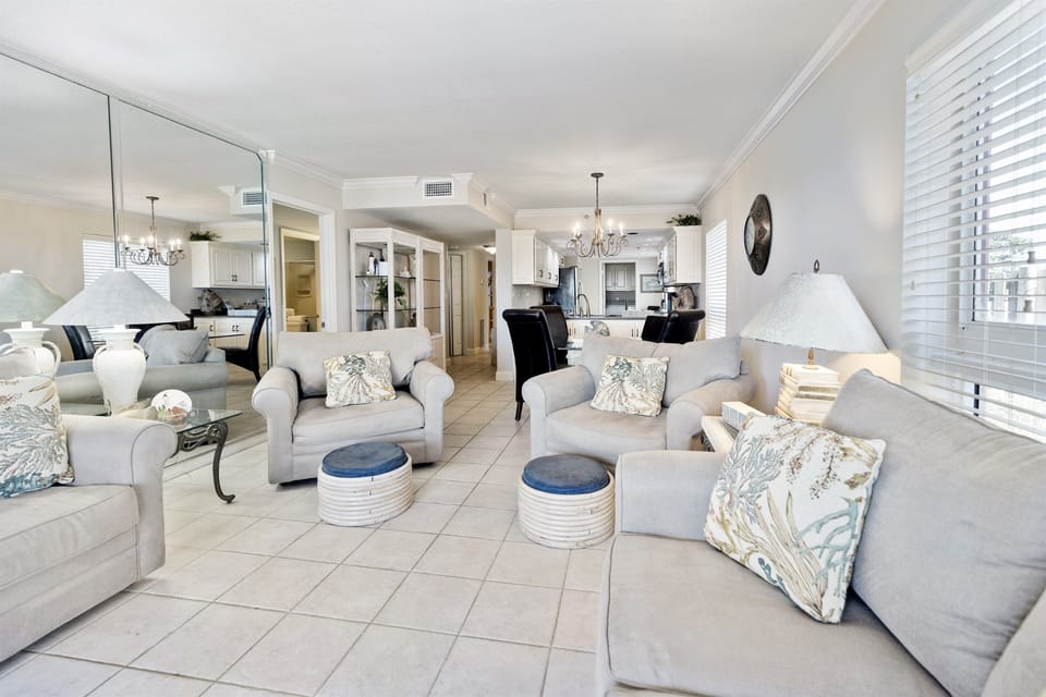 Relax in your bright, airy living room with plush seating and coastal decor, seamlessly connected to your fully equipped kitchen.