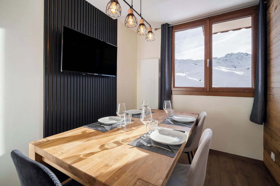 Window-side dining with piste views – raclette-ready table in our family-friendly Val Thorens rental.