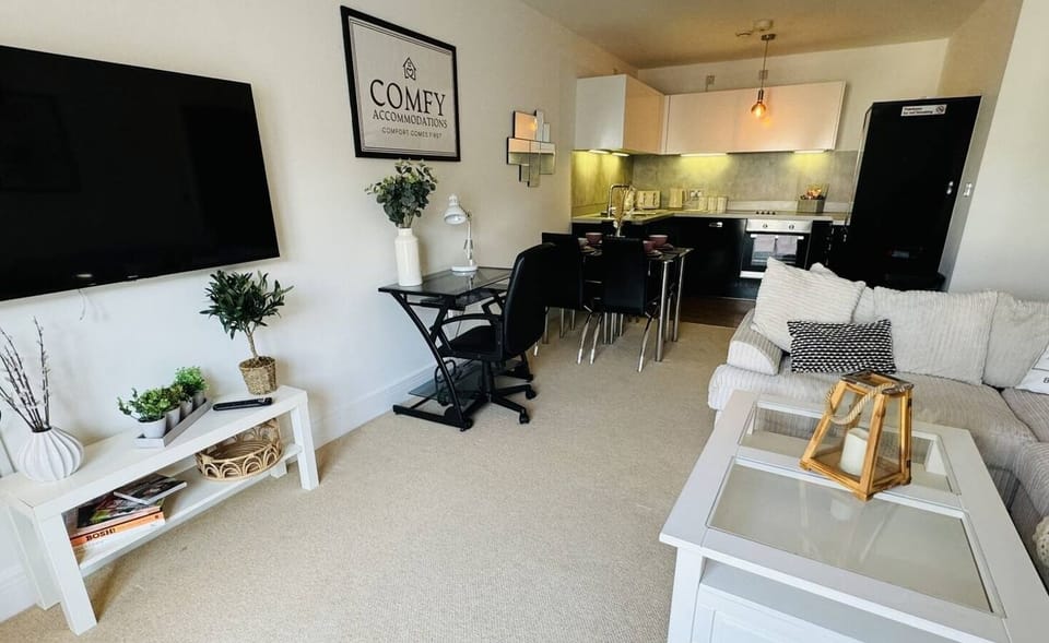 Modern open-plan living area with a smart TV, cozy seating, and a fully equipped kitchen—perfect for work or relaxation
