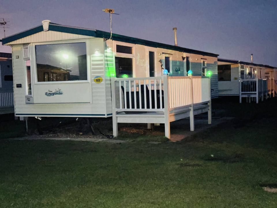 A well-lit, modern caravan at night, offering a welcoming and comfortable stay with ample outdoor space for guests to enjoy.