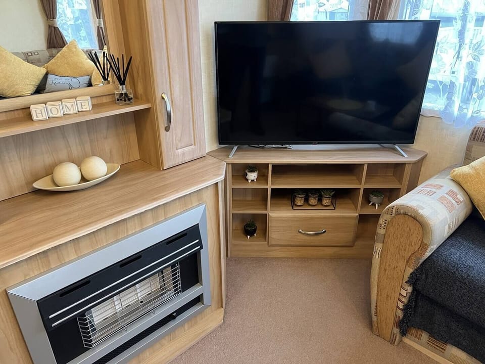 Cozy entertainment area with a large smart TV, fireplace & stylish décor—perfect for relaxing in your Skegness holiday home.