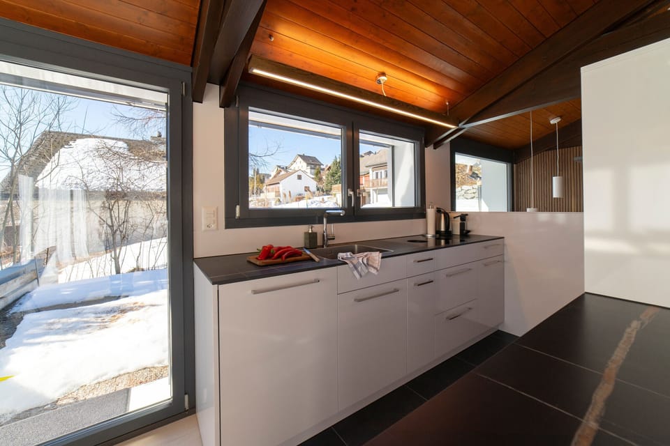 A modern kitchen with a view of the winter landscape and plenty of natural light