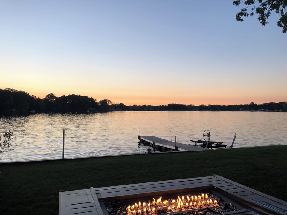 Gas fire pit on the lawn with the dock and lake beyond
