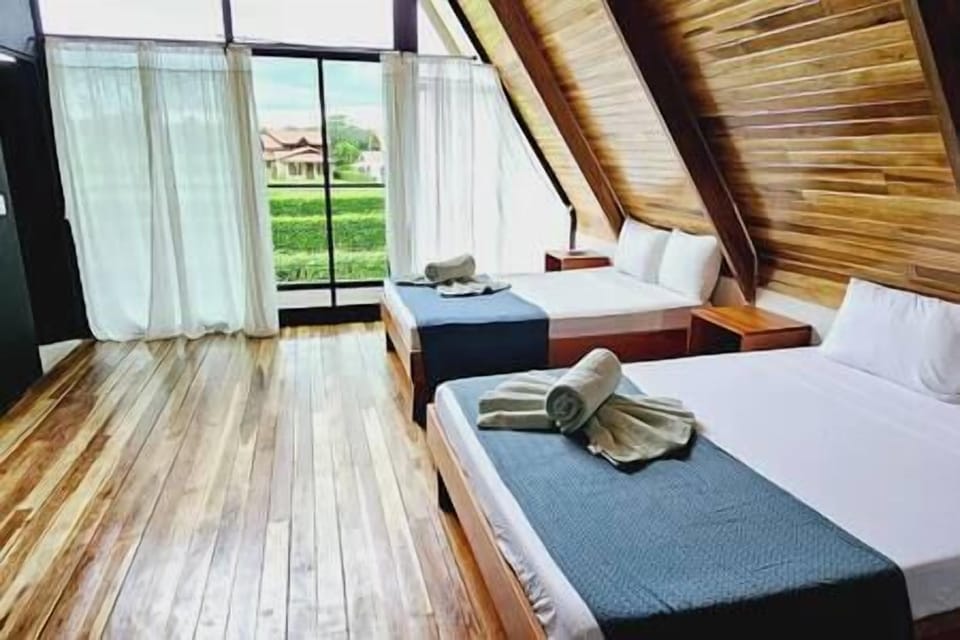 Pool view bedroom: two beds beneath the sloping wooden ceiling.