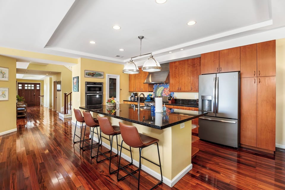 Bright, open kitchen with ample counter space, high-end appliances, and bar seating for four.