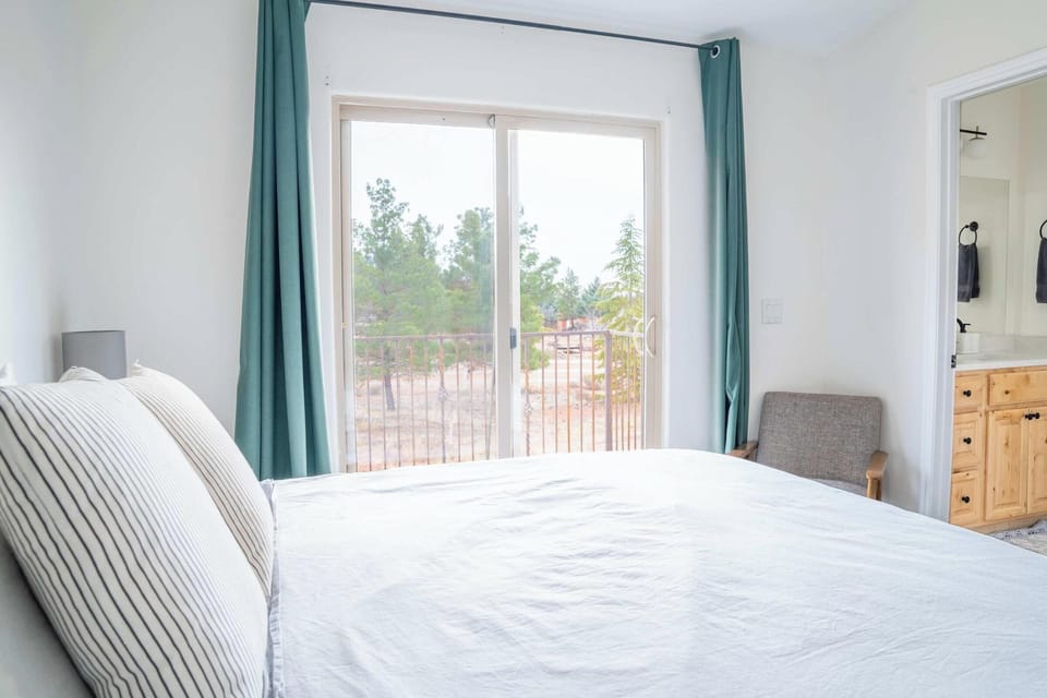 Cozy bedroom with balcony access and serene tree views at Kanab Pad F4.