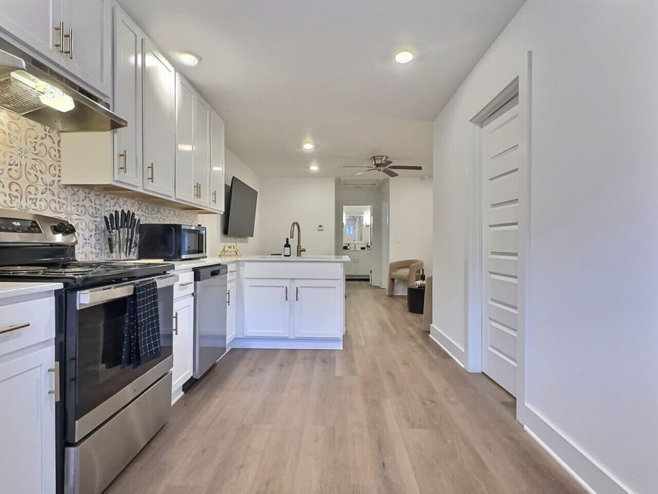 This kitchen features elegant white cabinetry complemented by chic gold hardware, offering a fresh and contemporary look.