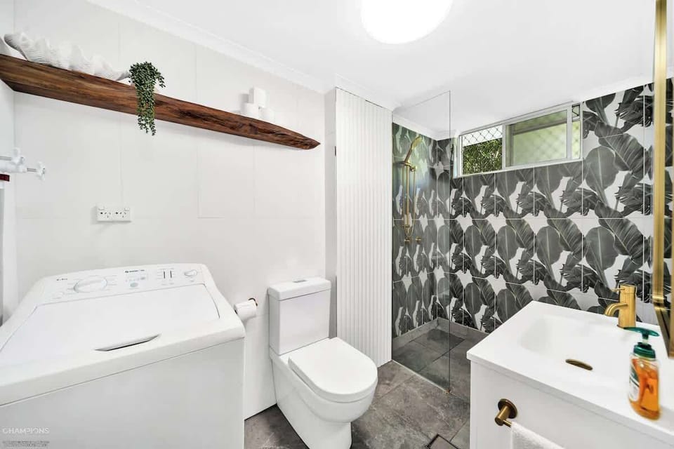 The bathroom offers a compact layout with a walk-in shower and washing machine.