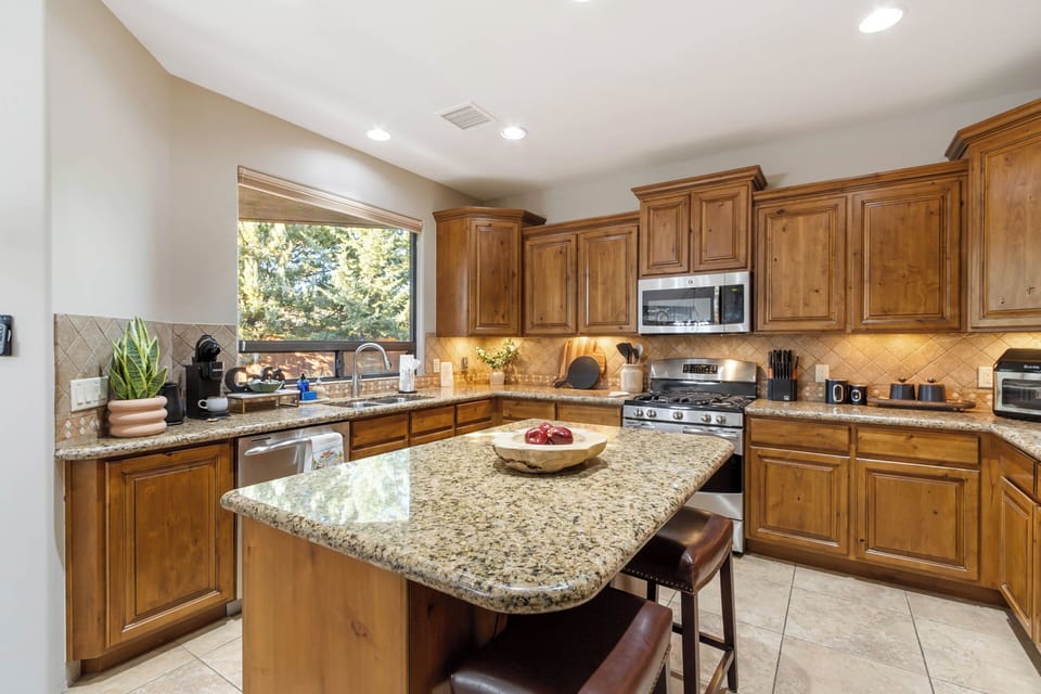 Granite countertops, stainless steel appliances, a walk-in pantry, and a central island with breakfast seating for two.