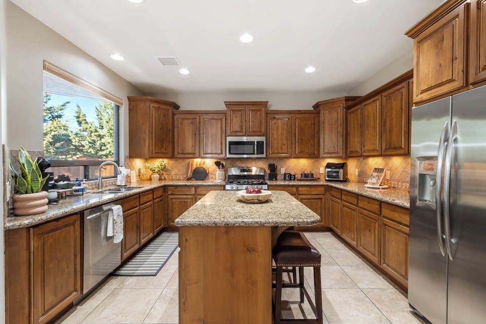 Granite countertops, stainless steel appliances, a walk-in pantry, and a central island with breakfast seating for two.