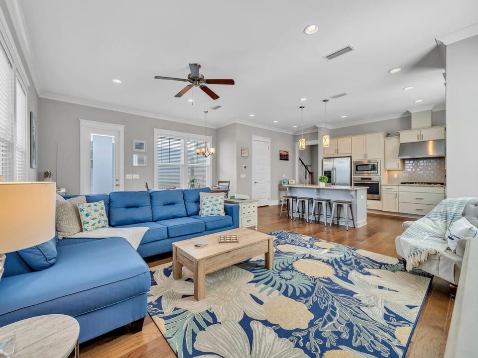 Relax in your spacious open-plan living area where coastal blue sofas and tropical patterns create the perfect beach house vibe.