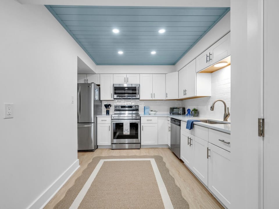 Cook your favorite meals in this fully equipped kitchen with stainless steel appliances and stunning blue ceiling accents.