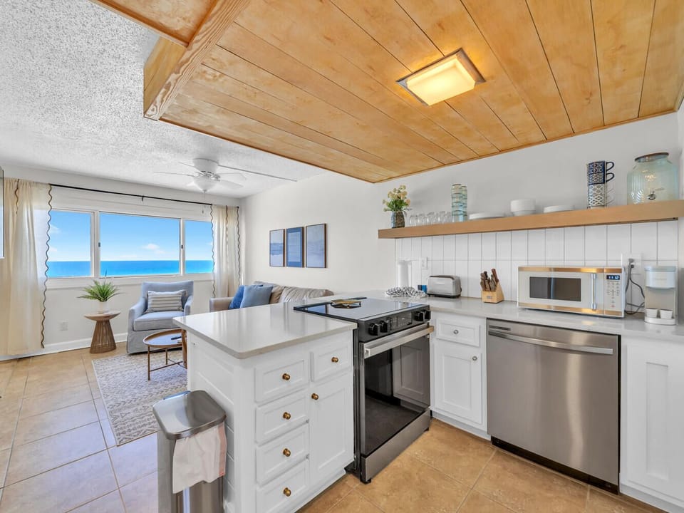 You'll love cooking with stunning ocean views in this bright kitchen featuring modern appliances and warm wood ceiling details.