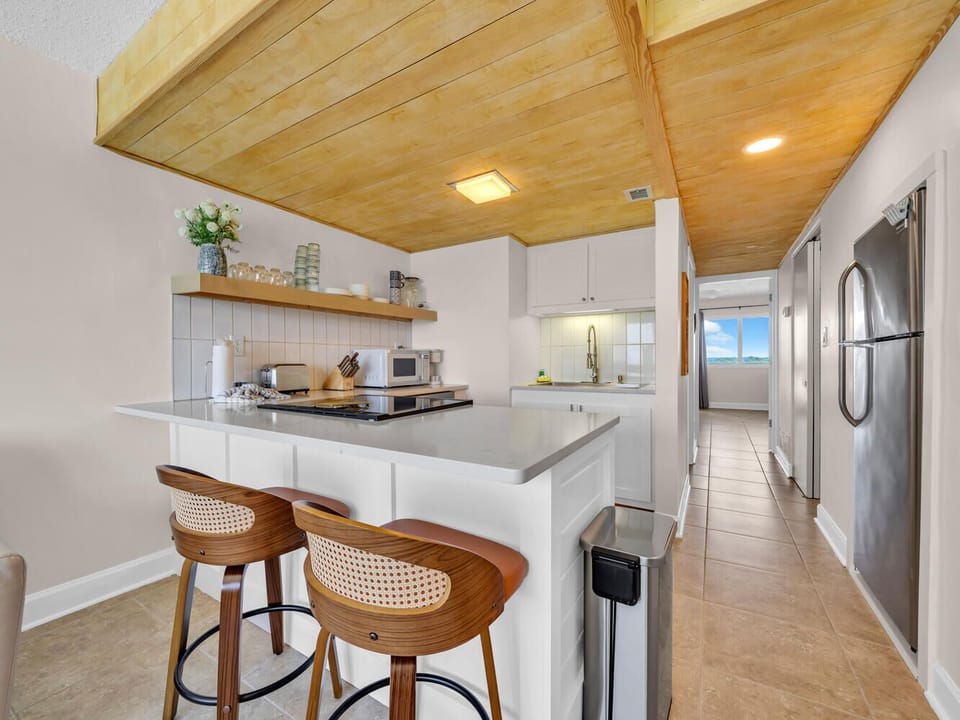 Cook your favorite meals in this stylish kitchen featuring warm wood ceilings, modern appliances, and a breakfast bar for casual dining.