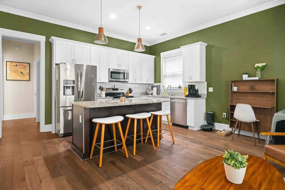 Bright white cabinets contrast beautifully with rich green walls, adding depth and personality to this kitchen.
