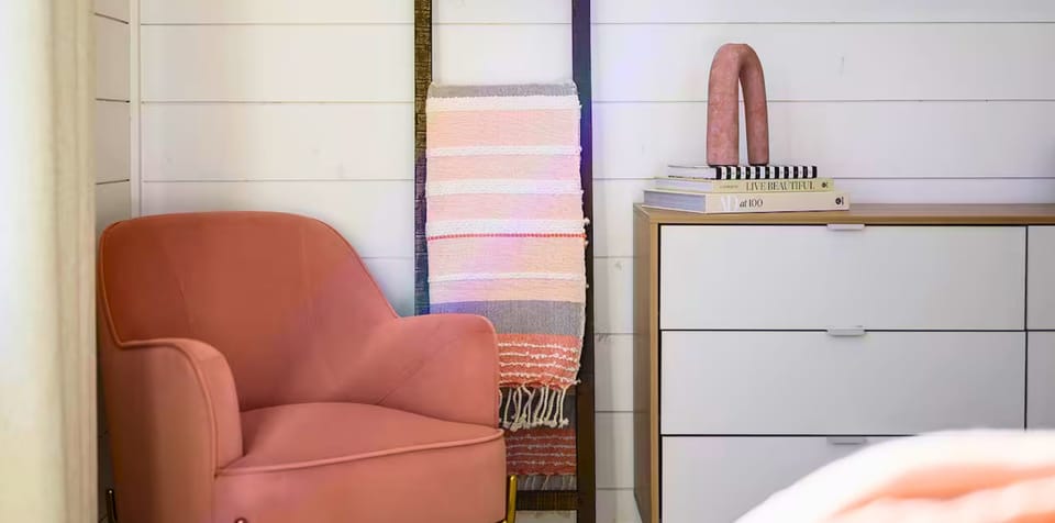 A charming corner with a blush accent chair and soft textiles, creating a perfect nook for reading or quiet reflection.