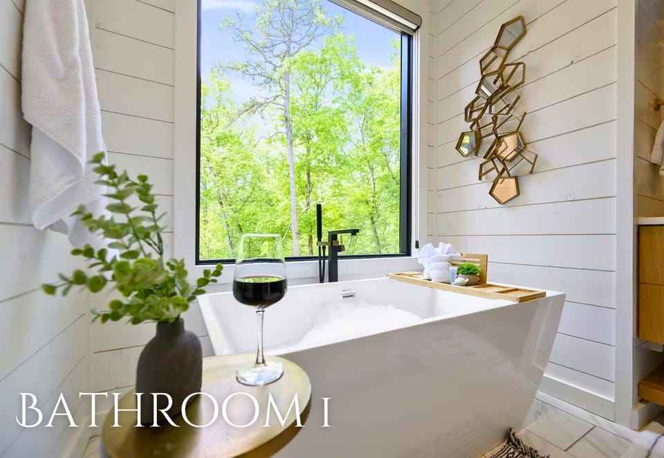Unwind in this luxurious soaking tub with a glass of wine in hand, surrounded by soft candlelight and a peaceful forest view.