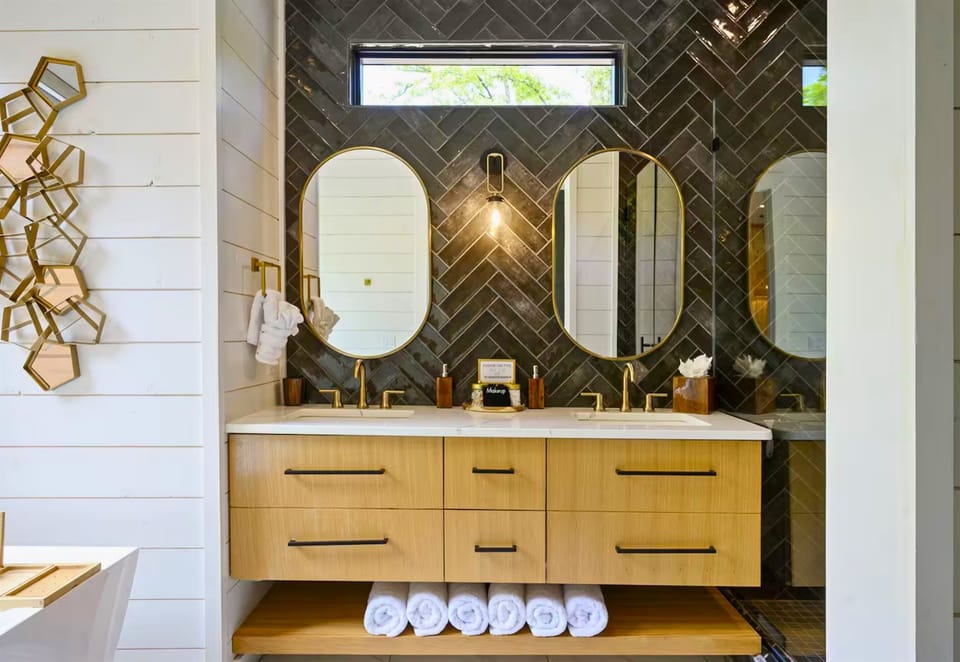 This spa-like bathroom offers the perfect blend of elegance and functionality, with dual sinks, warm wood tones, and statement mirrors.