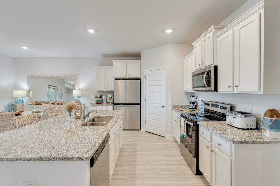 Step into your spacious gourmet kitchen featuring granite countertops, stainless steel appliances, and bright white cabinetry perfect for cooking memorable meals.