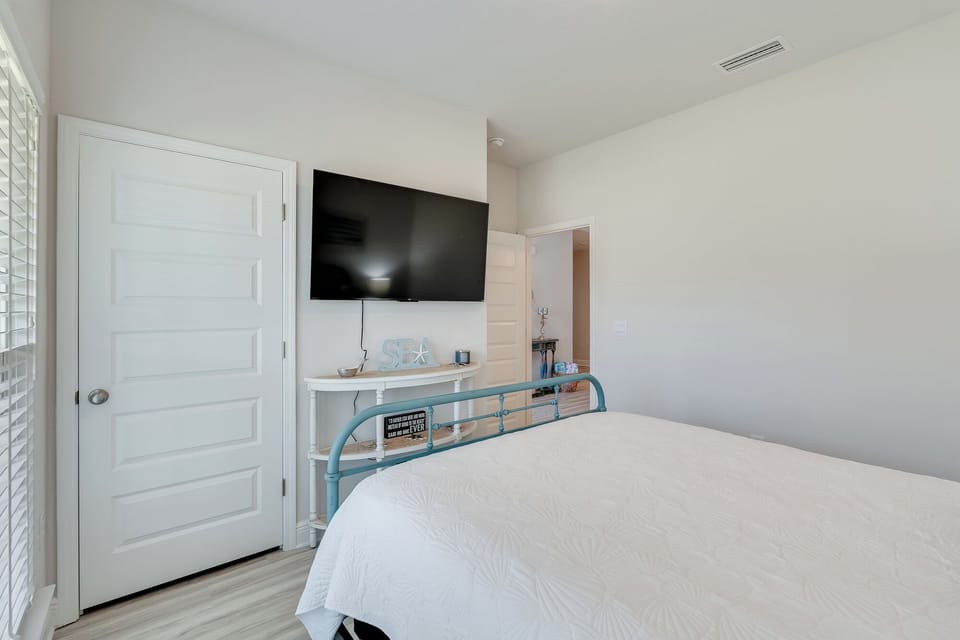 Unwind in your serene bedroom featuring a wall-mounted TV, crisp white linens, and modern amenities for ultimate relaxation.