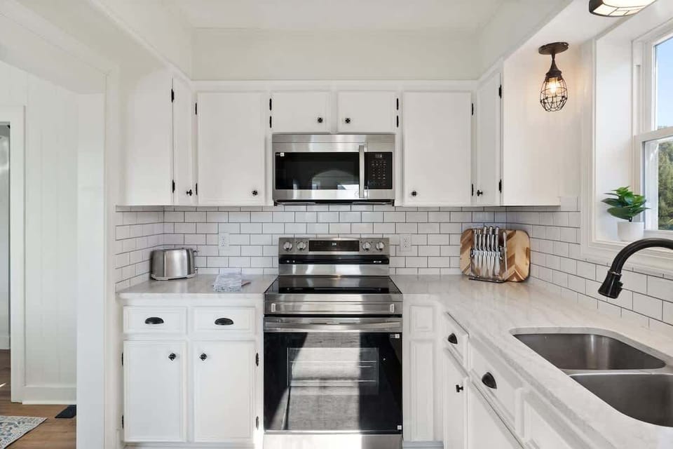 Bright kitchen with stainless range, subway tile backsplash, and double sink