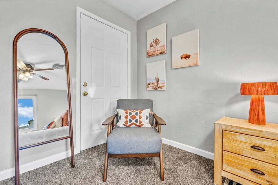 Right next to the chair is a mirror, framed in a way that enhances the room's aesthetic. The frame has a vintage feel with a wooden edge. The mirror’s size and placement ensure it reflects both the chair and the surrounding space.