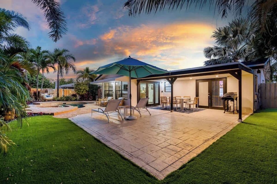 Covered patio and lawn at sunset, with dining and loungers.