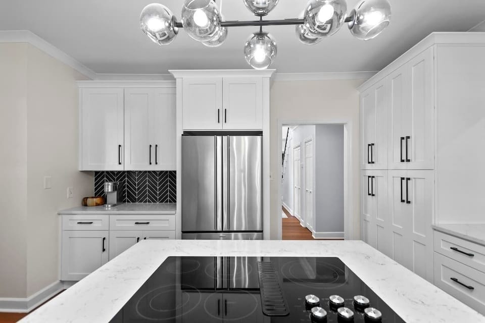 A large, airy, white kitchen with modern appliances and a clean, modern look.