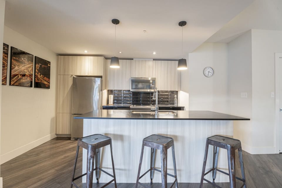 Welcome to the central social hub of your stay! This sleek, modern kitchen is designed for gathering and good times. Pull up one of the weathered metal barstools to the spacious island for casual conversation while someone whips up a feast, or enjoy a qui