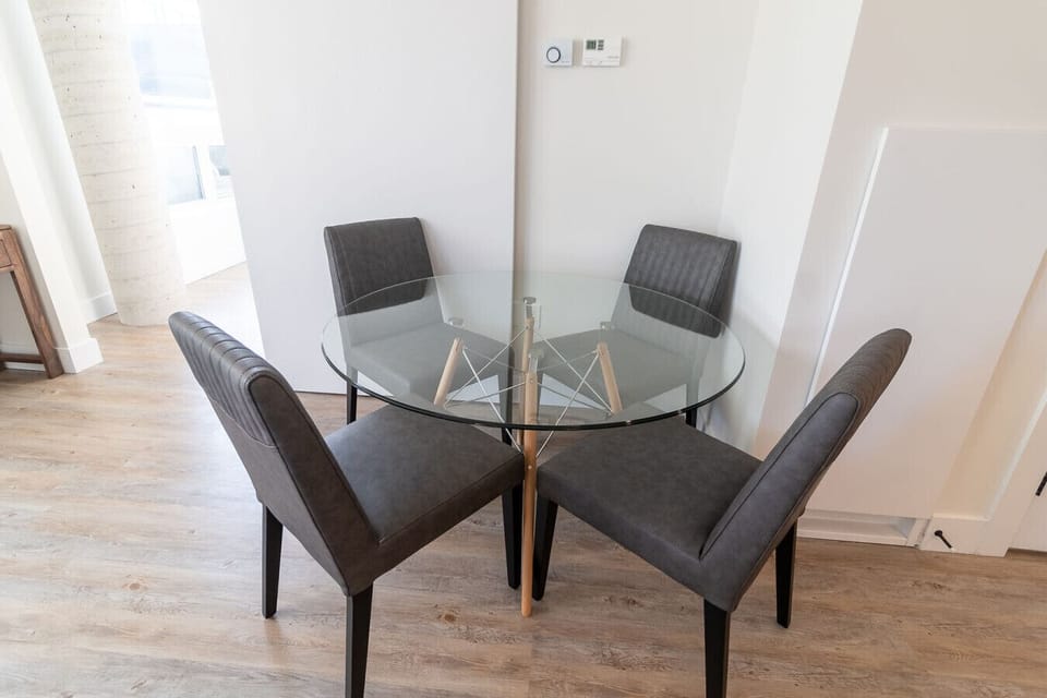 `Charming dining nook featuring a glass-top table paired with four upholstered chairs—perfect for casual meals or working from home.`