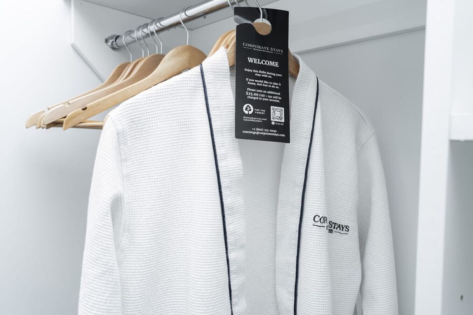 `Thoughtful guest amenities featuring a plush waffle-weave bathrobe hanging in the closet on a wooden hanger with a welcome tag.`