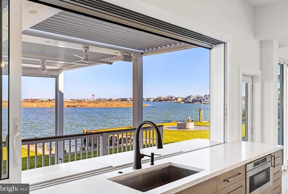 Main house kitchen window opens up to the outdoor kitchen and dining area