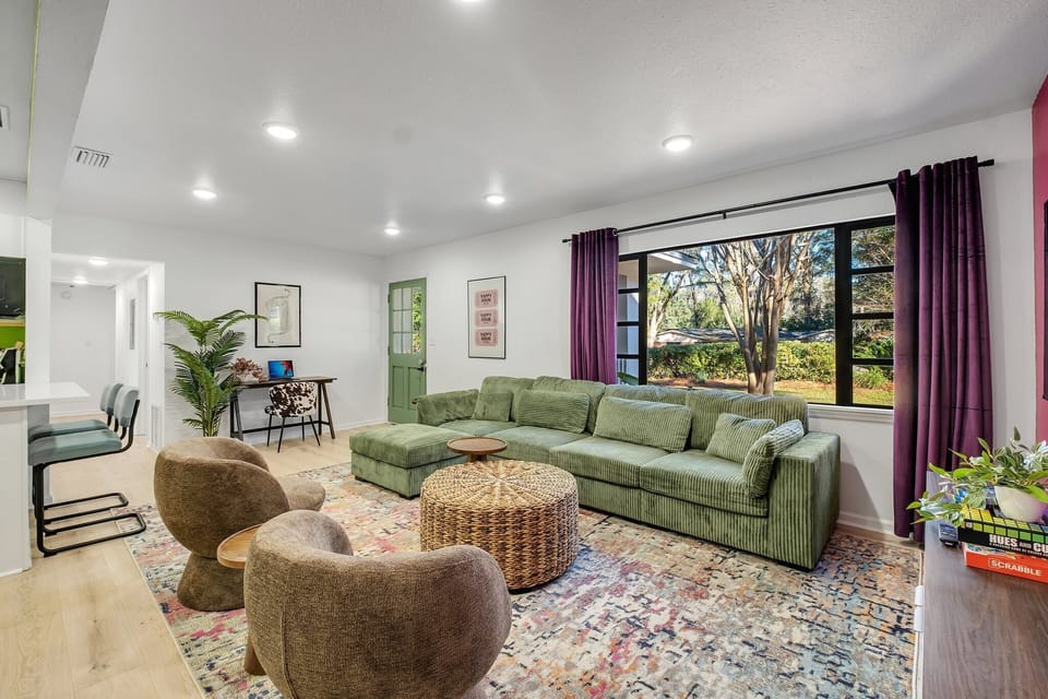 Living room with plush couch, dedicated workspace and windows with curtains