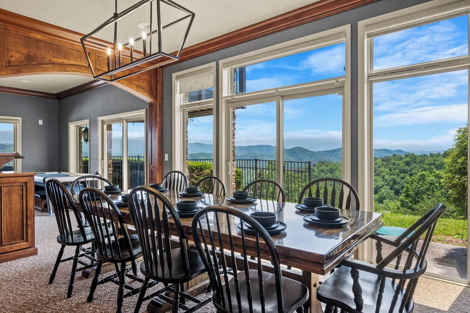 Long dining table backed by a wall of mountain windows