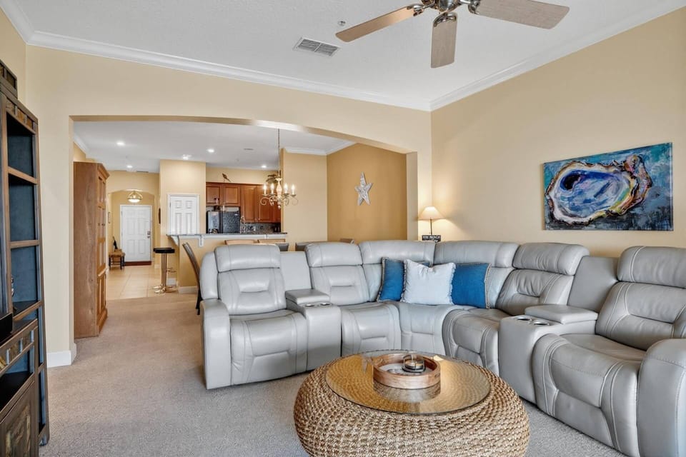 Open living space with a sectional sofa and theater-style reclining seats, smart cable-ready TV, and patio views for relaxing indoor-outdoor living.