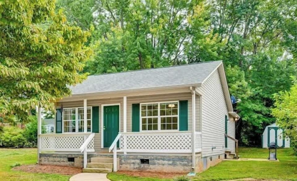 Charming home with a welcoming front porch, lush greenery, and a peaceful neighborhood setting.