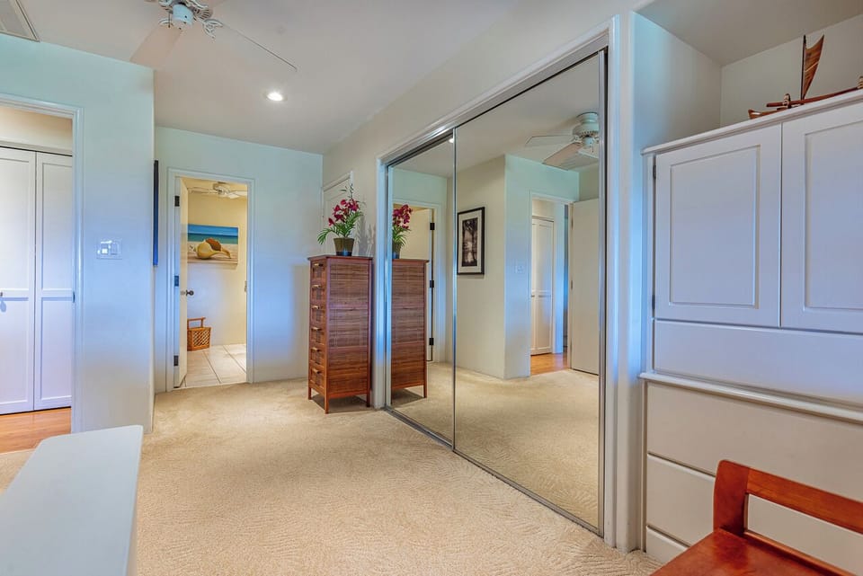 Your spacious bedroom features clean coastal colors, generous mirrored closets, and warm wood accents that create a serene retreat.