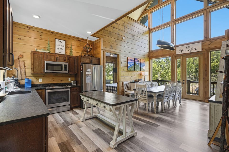 Gather around this stunning open kitchen with soaring windows that flood your space with natural light and forest views.