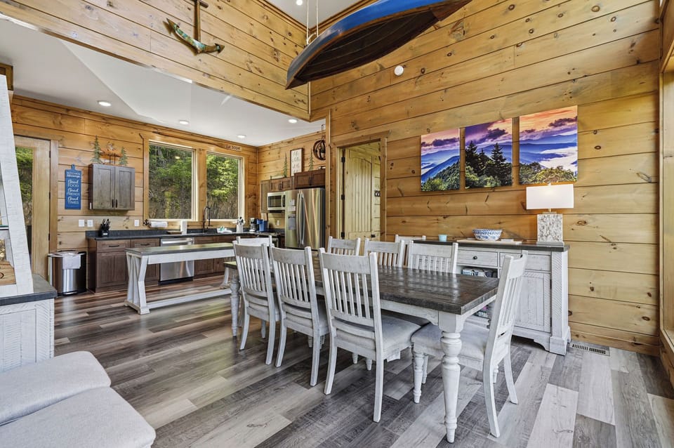 Gather around this beautiful dining table in your rustic-chic cabin. The warm wood walls and mountain artwork create the perfect backdrop for memorable meals.