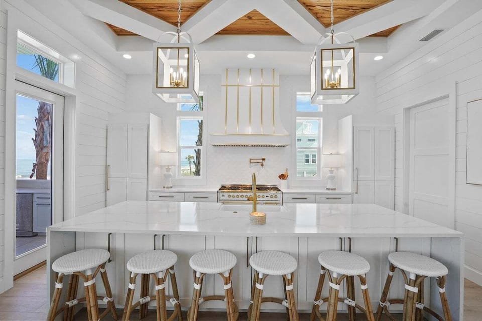 Enjoy ocean views while you cook in this stunning kitchen with its bright white cabinetry, gleaming countertops, and elegant pendant lighting.