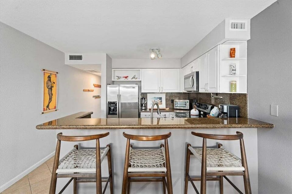Open kitchen with breakfast bar seating, granite countertops, and stainless steel appliances for convenient dining.