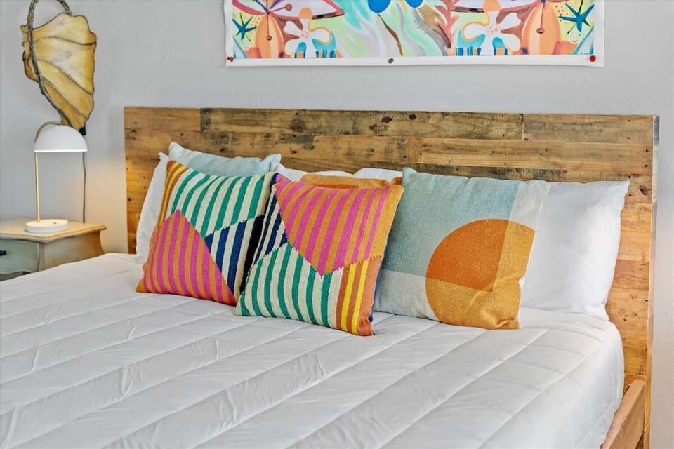 Close-up of the king-size bed with colorful accent pillows and stylish coastal-inspired bedroom décor.
